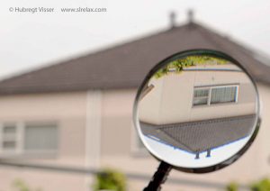 A magnifying glass showing trhe flipped image of a house on a far distance